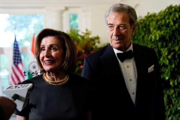 Two people in formal clothing speaking into a microphone during an interview.