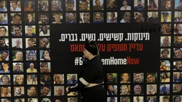 A woman walks by a wall covered with photos of hostages held in Gaza at a train station in Tel Aviv on 28 December